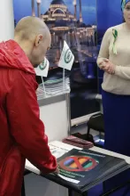 Посетители выставки разбирают брошюры